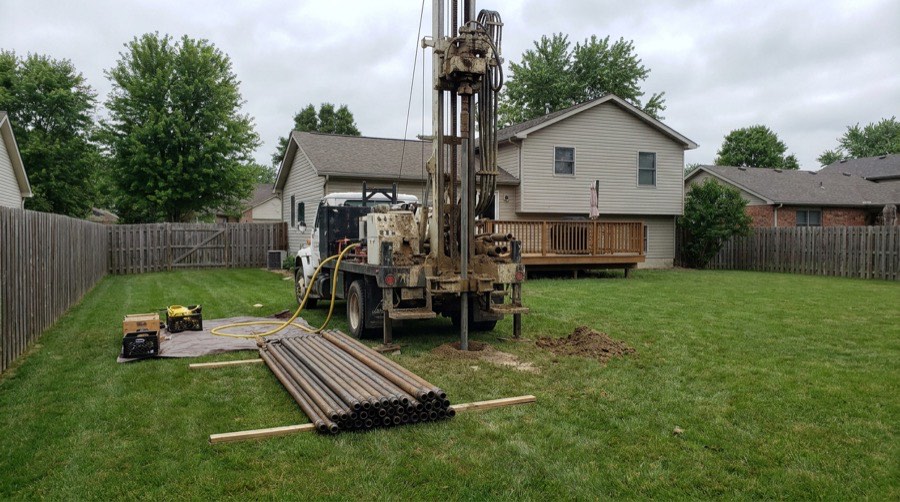 Geothermal vertical loop drilling rig in a residential yard
